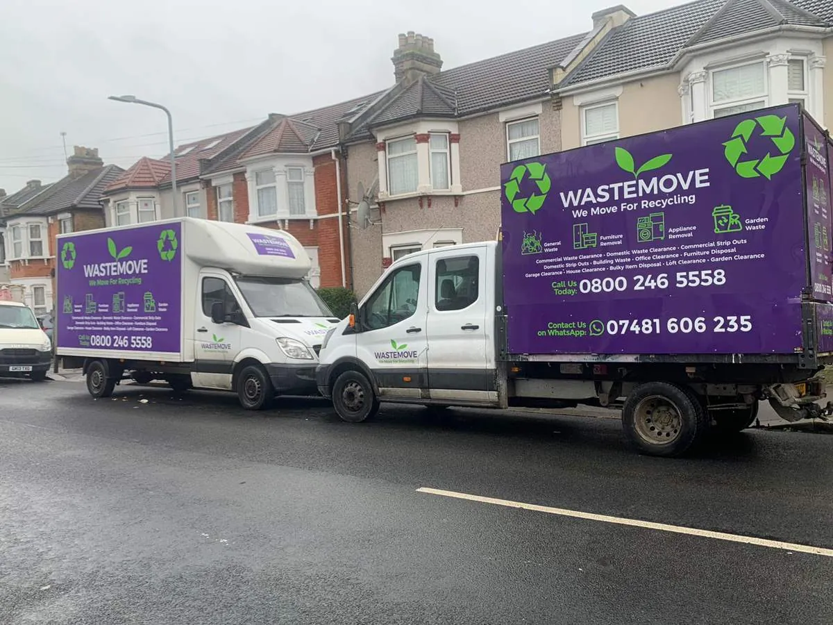 Two WasteMove vans, white cabs with purple branded bodies, parked on a residential street in Ilford
